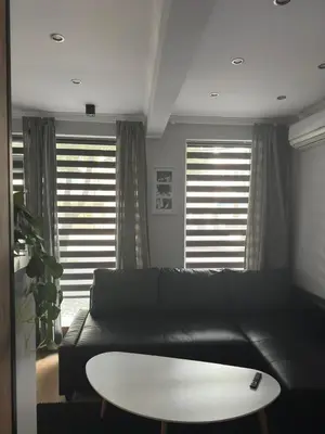 a living room with a black couch and a table at Casa Raffaelo in Burgas City