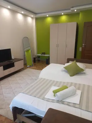 a bedroom with a large white bed with green walls at Guest House Dani in Pomorie