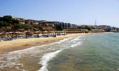 a beach with chairs and umbrellas and the ocean at Olymp SkyView Apartment in Sveti Vlas
