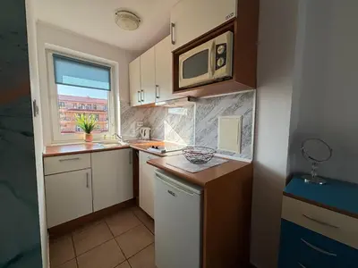 a small kitchen with white cabinets and a window at BW - Aquamarin C6 in Sunny Beach