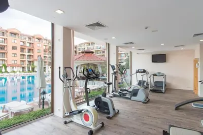 a fitness room with cardio equipment and a swimming pool at Прекрасно място за нощувки в Слънчев бряг in Sunny Beach