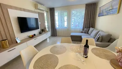 a living room with a table with chairs and a television at Luxus und Komfort im Vista Residence Komplex in Sveti Vlas