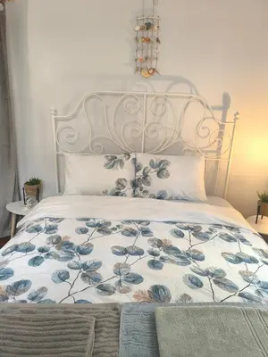 a bed with a metal headboard with blue flowers on it at Apartment Compass- Super Center Burgas in Burgas City