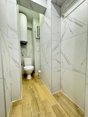 a bathroom with a toilet and marble walls at Apartment Compass- Super Center Burgas in Burgas City