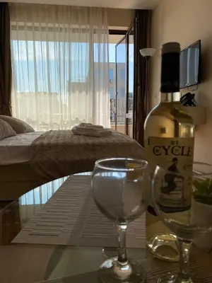 a bottle of wine and two wine glasses on a table at Privet apartament in Premier Fort in Sveti Vlas