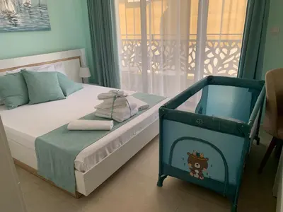 a small bedroom with a bed and a balcony at Sea Sunrise Apartment Sozopol in Sozopol