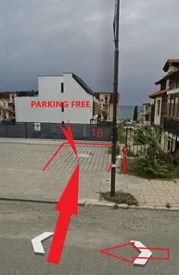 a red arrow pointing to a parking free sign on the street at Sea Sunrise Apartment Sozopol in Sozopol