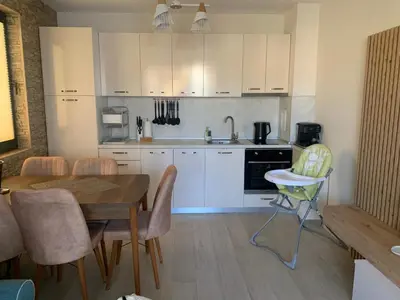 a kitchen with white cabinets and a table and chairs at Sea Sunrise Apartment Sozopol in Sozopol