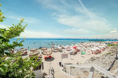 a beach with many umbrellas and people in the water at Prestige Fort Aparthotel - Private apartment - BSR - 1 in Sveti Vlas