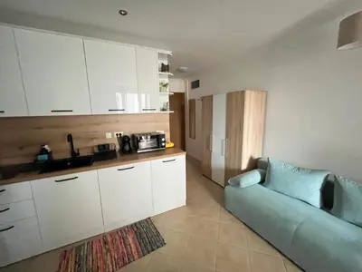 a living room with a blue couch and a kitchen at Aquamarine Studio in Santa Marina in Sozopol