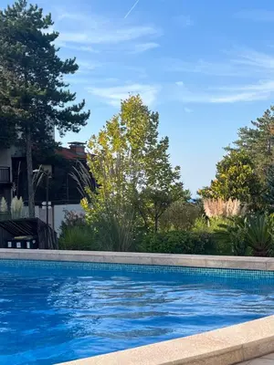 a swimming pool in front of a house with trees at Aquamarine Studio in Santa Marina in Sozopol