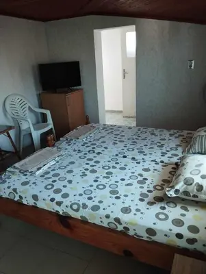 a bedroom with a large bed with a television and a chair at Къща за гости дом Попови Черноморец in Chernomorets