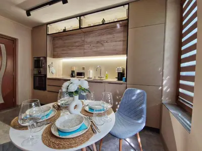 a dining room with a table and chairs and a kitchen at Delux Apart Vulchevi with Parking in Burgas City