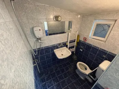 a blue tiled bathroom with a toilet and a sink at Вила 50 in Atiya