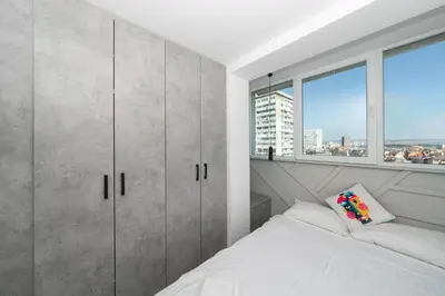 a white bedroom with a bed and a window at Lazur Sea View in Burgas City