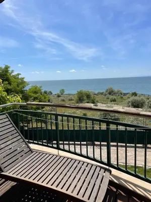a wooden bench sitting on a balcony overlooking the ocean at Private apartments Ravda-Emerald in Ravda