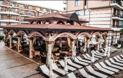 a gazebo with white chairs and a building at Karolina complex appartment in Sunny Beach