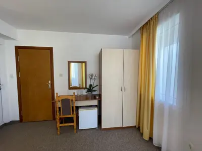 a room with a desk and a cabinet and a mirror at Alatoni Beach Hotel in Sozopol