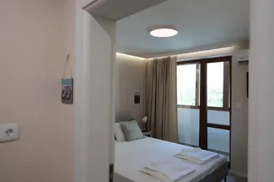 a bedroom with a white bed and a window at Azur Holiday Burgas - self check-in in Burgas City
