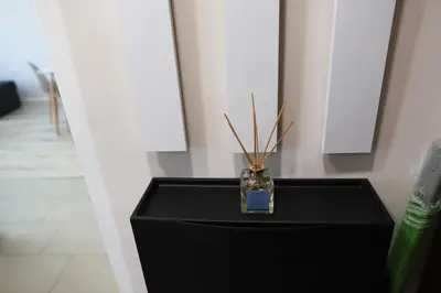 a black table with a vase with sticks in it at Azur Holiday Burgas - self check-in in Burgas City