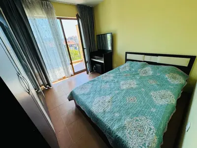 a bedroom with a bed with a green comforter and a window at AMADEUS I B31 Apartment Sunny Beach in Sunny Beach