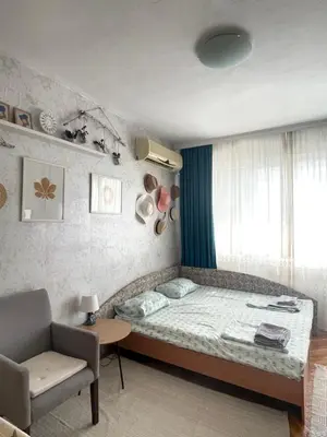 a bedroom with a bed and a chair and a window at BOHO Apartment in Varna City