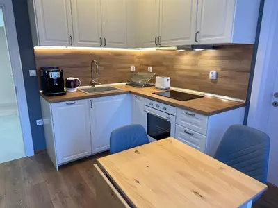 a kitchen with white cabinets and a table and a sink at Romantic City Central Apartment in Varna City