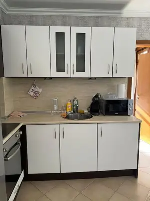a kitchen with white cabinets and a sink and a microwave at Niko's Apartment in Sozopol