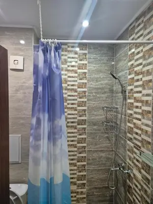 a bathroom with a shower with a blue shower curtain at Делукс Апарт Вергиеви in Burgas City