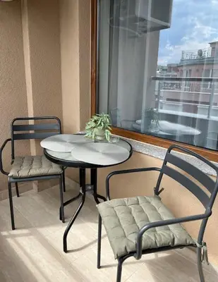 a table and chairs on a balcony with a window at New and stylish apartment Tuthon in Pomorie