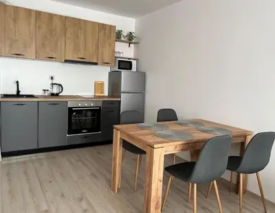 a kitchen with a wooden table and some chairs at New and stylish apartment Tuthon in Pomorie