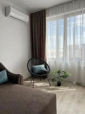 a living room with a chair and a window at New and stylish apartment Tuthon in Pomorie