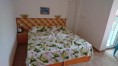 a bedroom with a bed with a floral bedspread at Sianie Guest House in Ravda