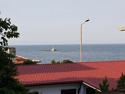 a boat in the water with a lighthouse in the ocean at Вила Мила in Tsarevo