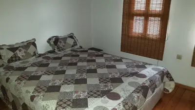 a bedroom with a quilt on a bed with a window at Вила Мила in Tsarevo