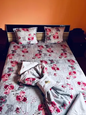 a bed with pink flowers and blankets and pillows at Къща за гости ФОРЕВЪР in Banya