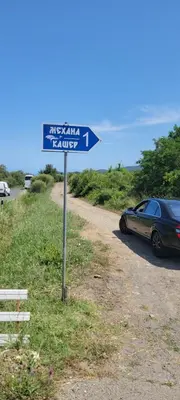 a blue street sign next to a car on a road at Къща за гости ФОРЕВЪР in Banya