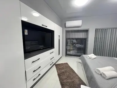 a white bedroom with a flat screen tv and a bed at NJ bedroom in Varna City