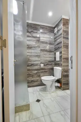 a bathroom with a toilet and wooden wall at Private 1-BD Apartment with Balcony in Sveti Vlas by Flat Mаnаger in Sveti Vlas