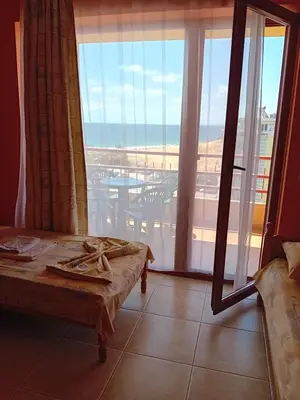 a room with a bed and a view of the ocean at Златна Дюна - до южния плаж на Несебър in Nesebar