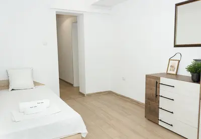 a white bedroom with a bed and a dresser at Bright 2-Bedroom Apartment Near Varna City Center by Flat Mаnаger in Varna City