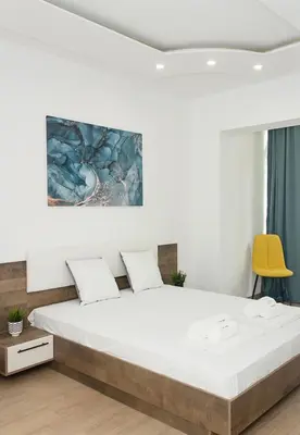 a bedroom with a large bed and a yellow chair at Bright 2-Bedroom Apartment Near Varna City Center by Flat Mаnаger in Varna City