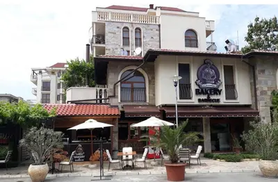 a restaurant with tables and umbrellas in front of a building at Luxury Apartments in Cascadas Family Resort Sunny Beach in Sunny Beach