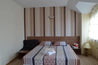 a bedroom with a bed with a striped wall at Stella Del Mare Guest House in Kiten
