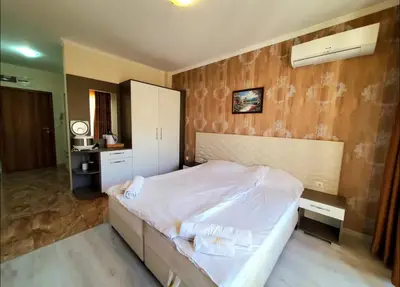 a bedroom with a white bed and a wooden wall at Уютно студио до морето - апартаменти 25 и 26, топ локация - Cozy Studio by the Sea - Apartments 25 and 26 Top Location in Sveti Vlas