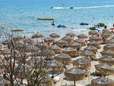 a beach with umbrellas and people in the water at Guest Apartment Rusalka in Sveti Vlas