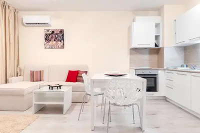 a kitchen and living room with a white table and chairs at АТ apartment - Pool View in Varna City