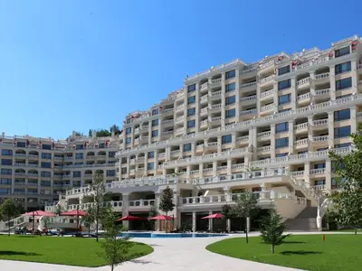 a large building with red umbrellas in front of it at АТ apartment - Pool View in Varna City