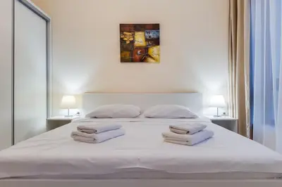 a white bed with three towels on top of it at АТ apartment - Pool View in Varna City