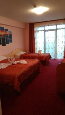 a hotel room with three beds and a window at Guest House Aristokrat in Obzor